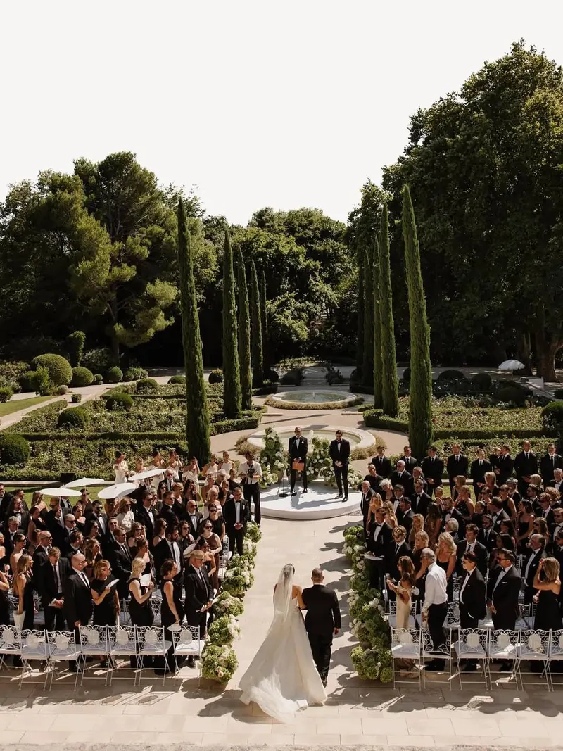 Vue aérienne d’une cérémonie de mariage dans des jardins à la française bordés de cyprès