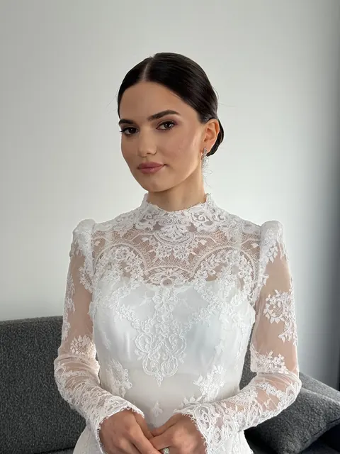 Bride in high-neck lace gown with sleek low bun and natural bridal makeup