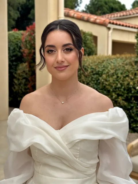 Mariée en robe épaules dénudées et chignon romantique dans le jardin ensoleillé d’une villa
