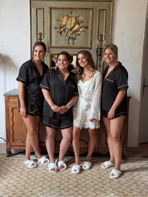 La mariée en peignoir blanc et ses demoiselles d’honneur en pyjama noir se préparent ensemble
