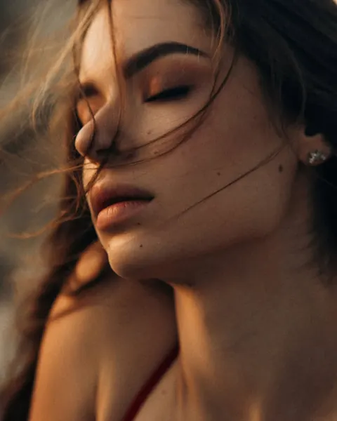 Close-up of bronze eyeshadow and soft matte lips, eyes closed, windswept hair