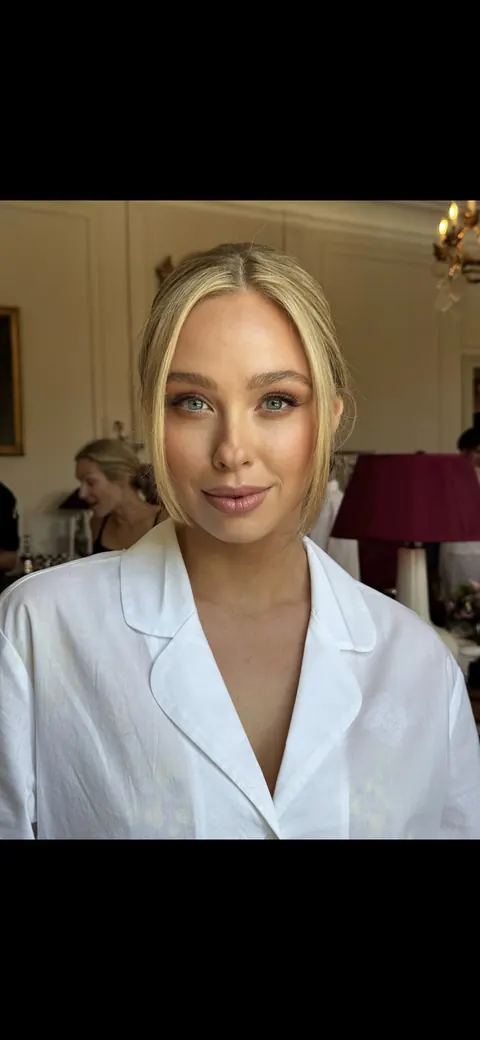 Getting ready: sleek tucked blonde hair and natural makeup, white shirt, vertical frame