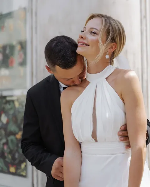 Groom kissing bride's shoulder, bride in halter gown with soft updo