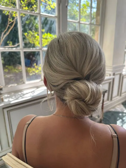 Low textured chignon seen from behind in a bright room with garden windows