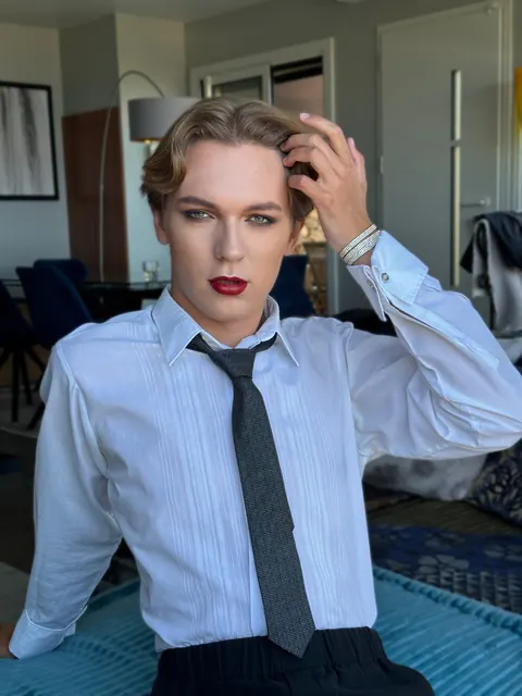 Male model with red lips and smoky eyes in shirt and loose tie, editorial look