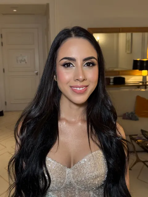 Smiling woman with long sleek dark hair, glam lashes and sparkly corset top