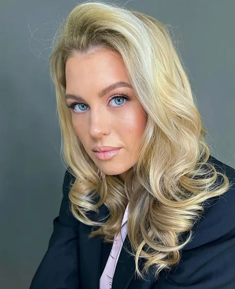 Voluminous blonde blowout waves with soft glam makeup, navy blazer portrait