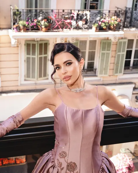 Femme en robe de satin vieux rose et longs gants sur un balcon, chignon lisse