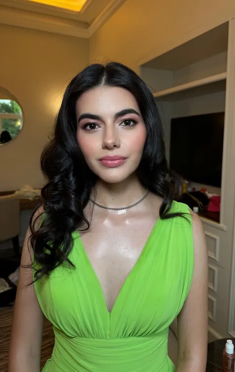Woman in lime green dress with voluminous dark curls and glam makeup