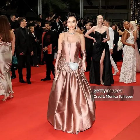 Woman in rose satin ball gown and long gloves on a crowded red carpet, glam makeup