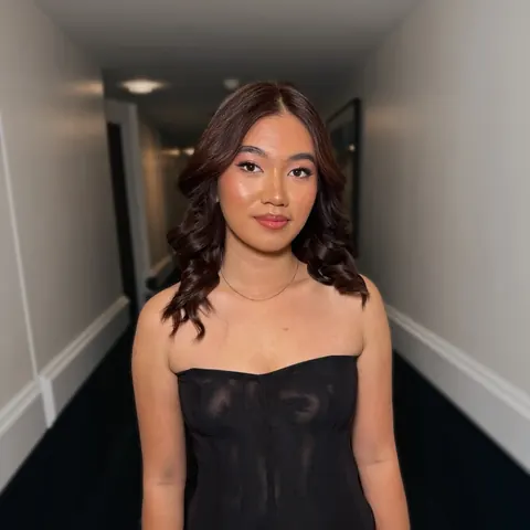 Femme aux boucles brunes souples et maquillage lumineux en haut bustier noir