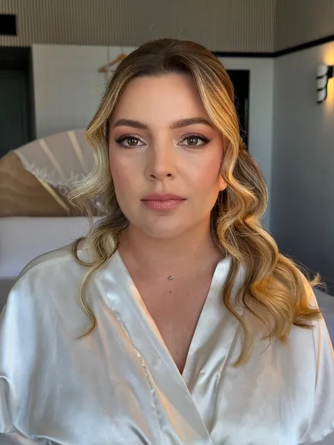 Woman in white satin robe with soft Hollywood waves and defined eye makeup